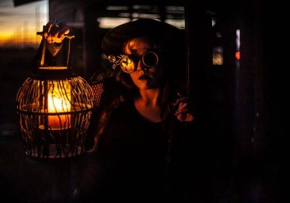 woman with steampunk eyeglasses holding a lantern